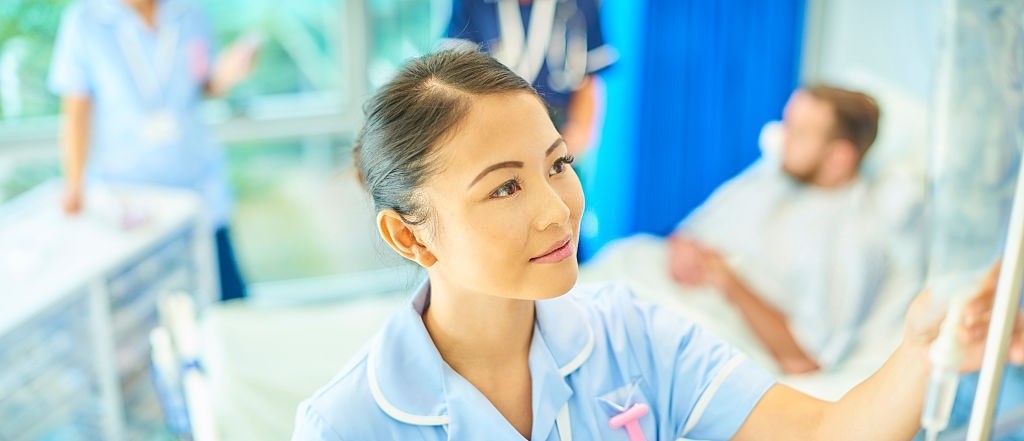 a nurse is attending to a saline drip on a hospital ward 
