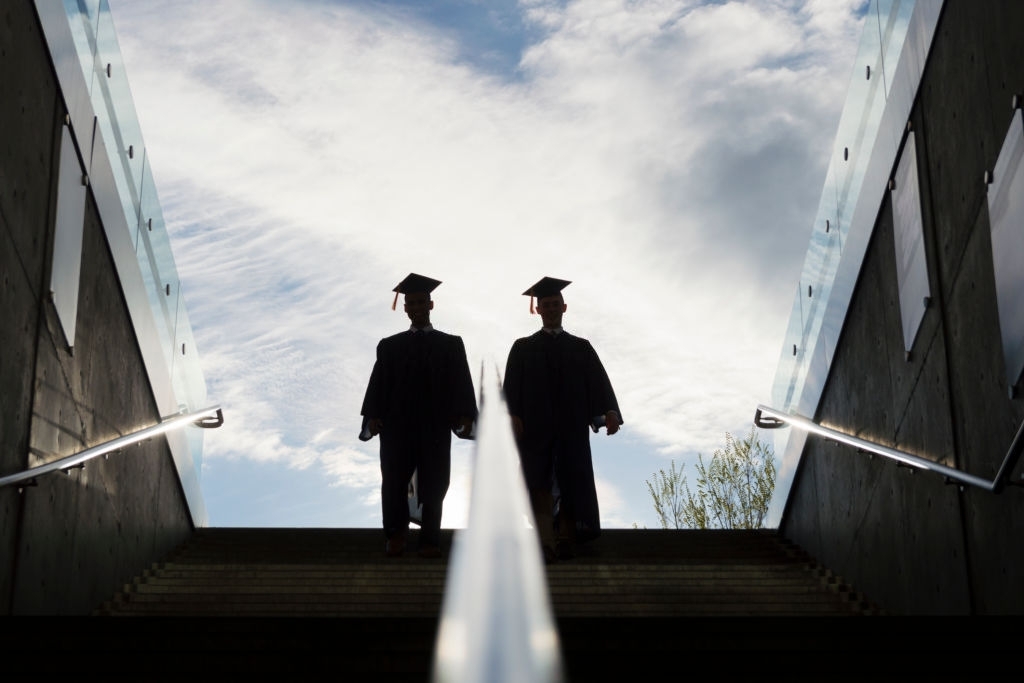 Silhouette of Two College Graduates Climbing Steps